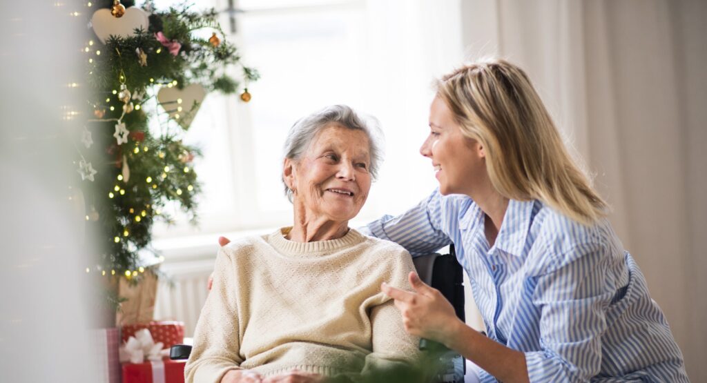 Senior woman in wheelchair talking to family member by Christmas tree
