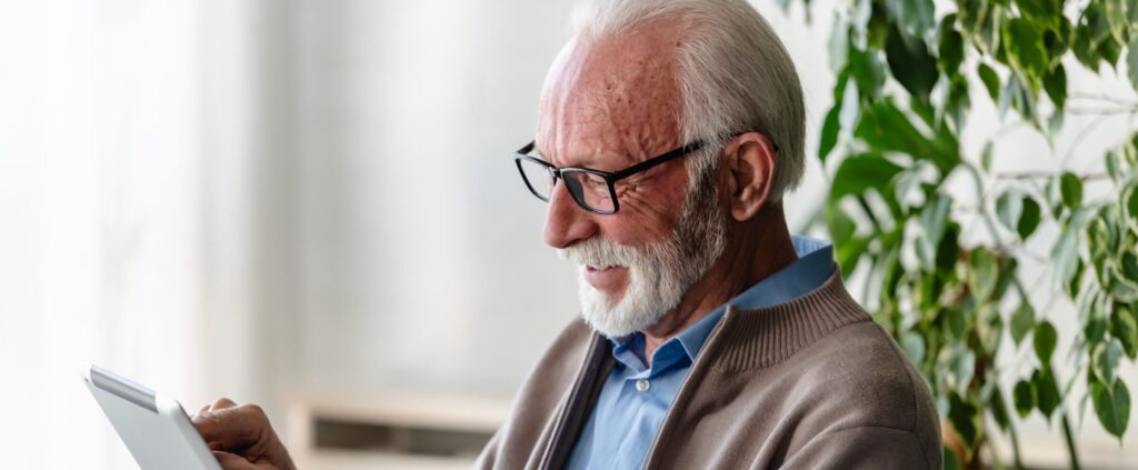 Senior man smiling using a tablet