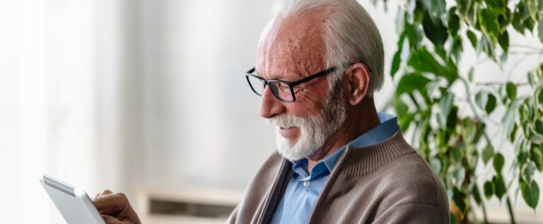 Senior man smiling using a tablet